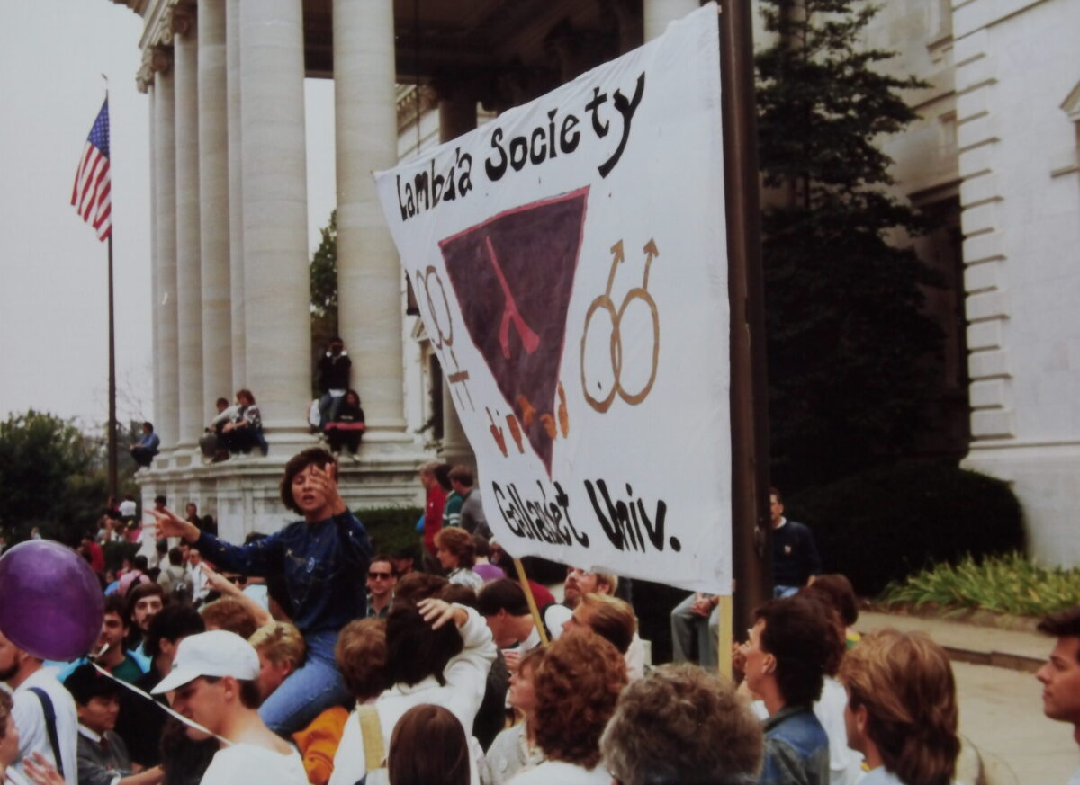 Marchers holding a banner reading "Lambda Society Gallaudet Univ" with a pink triangle symbol in the middle.